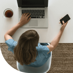 High view of person working on laptop while authenticating with mobile phone